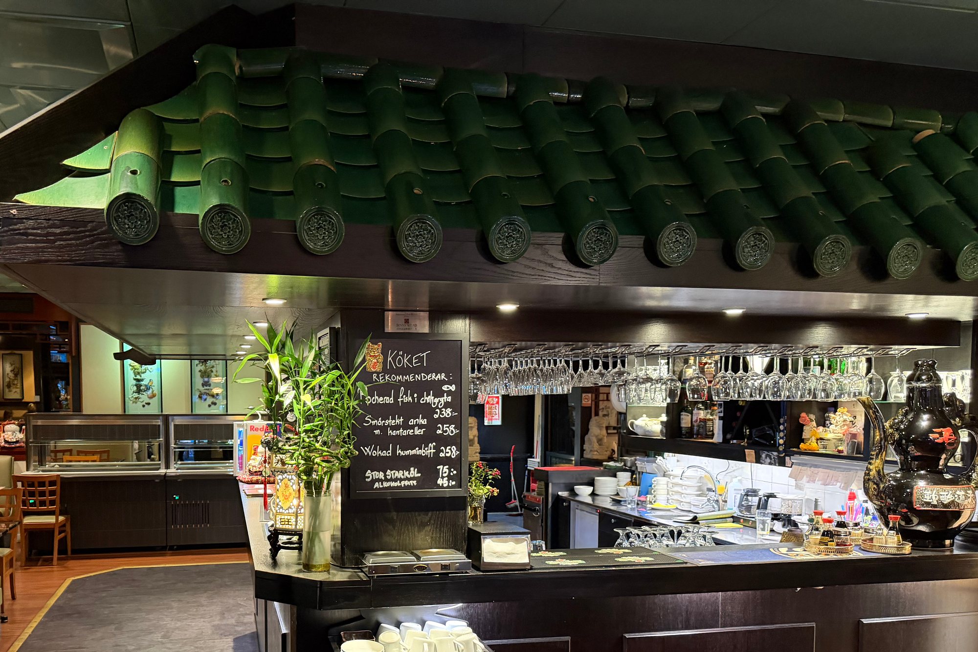 Baren under det gröna taket med gröna takpannor, vinglas och tavlan Köket rekommenderar